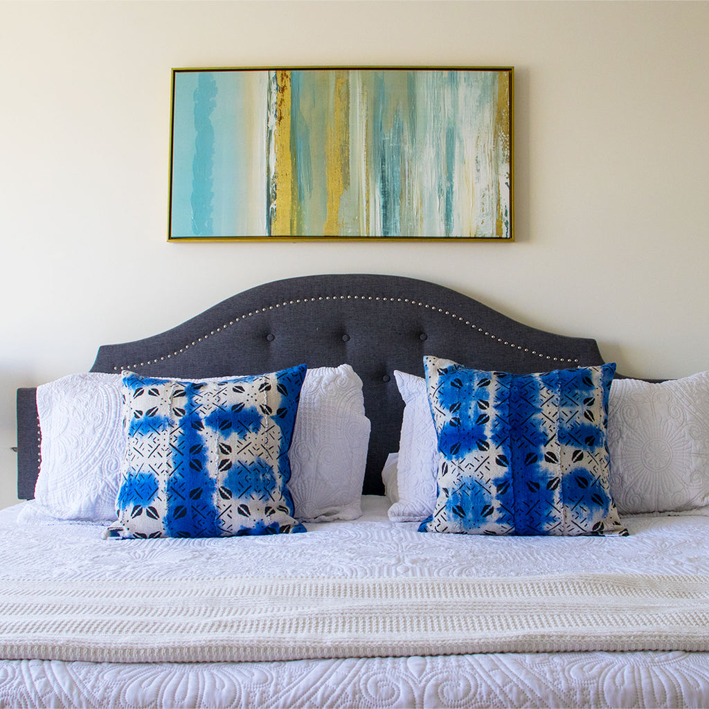 Bedroom with a bed featuring blue and white patterned mud cloth pillows