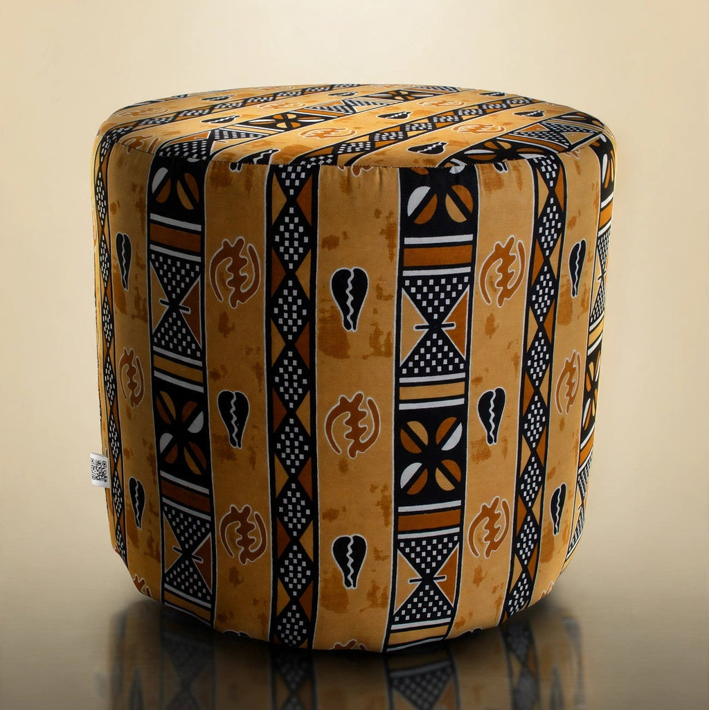 Handmade drum pouf ottoman in golden amber African wax print with black geometric symbols — front angled view