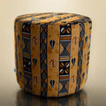 Handmade drum pouf ottoman in golden amber African wax print with black geometric symbols — front angled view