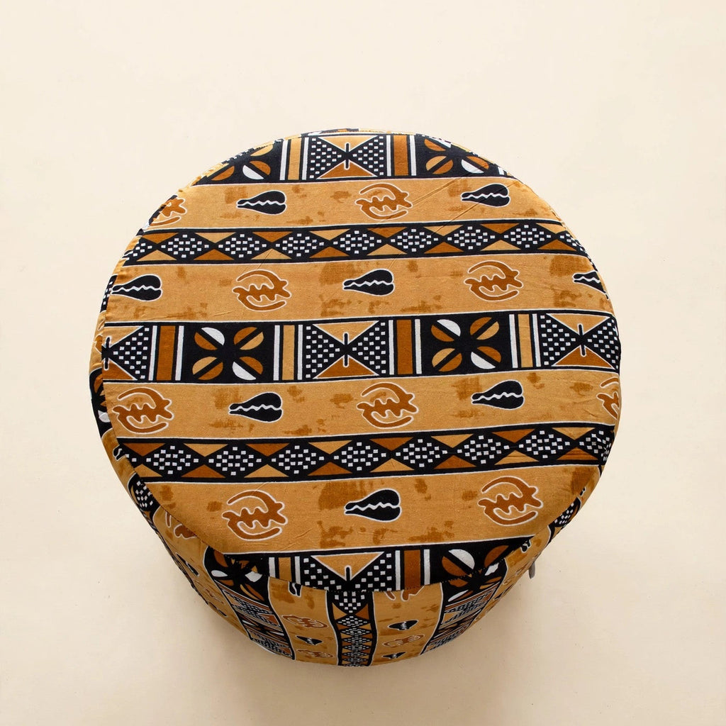 Top-down view of the Drum Pouf ottoman in golden African wax print with horizontal stripe patterns and Adinkra symbols