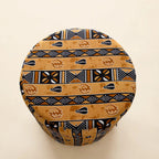 Top-down view of the Drum Pouf ottoman in golden African wax print with horizontal stripe patterns and Adinkra symbols